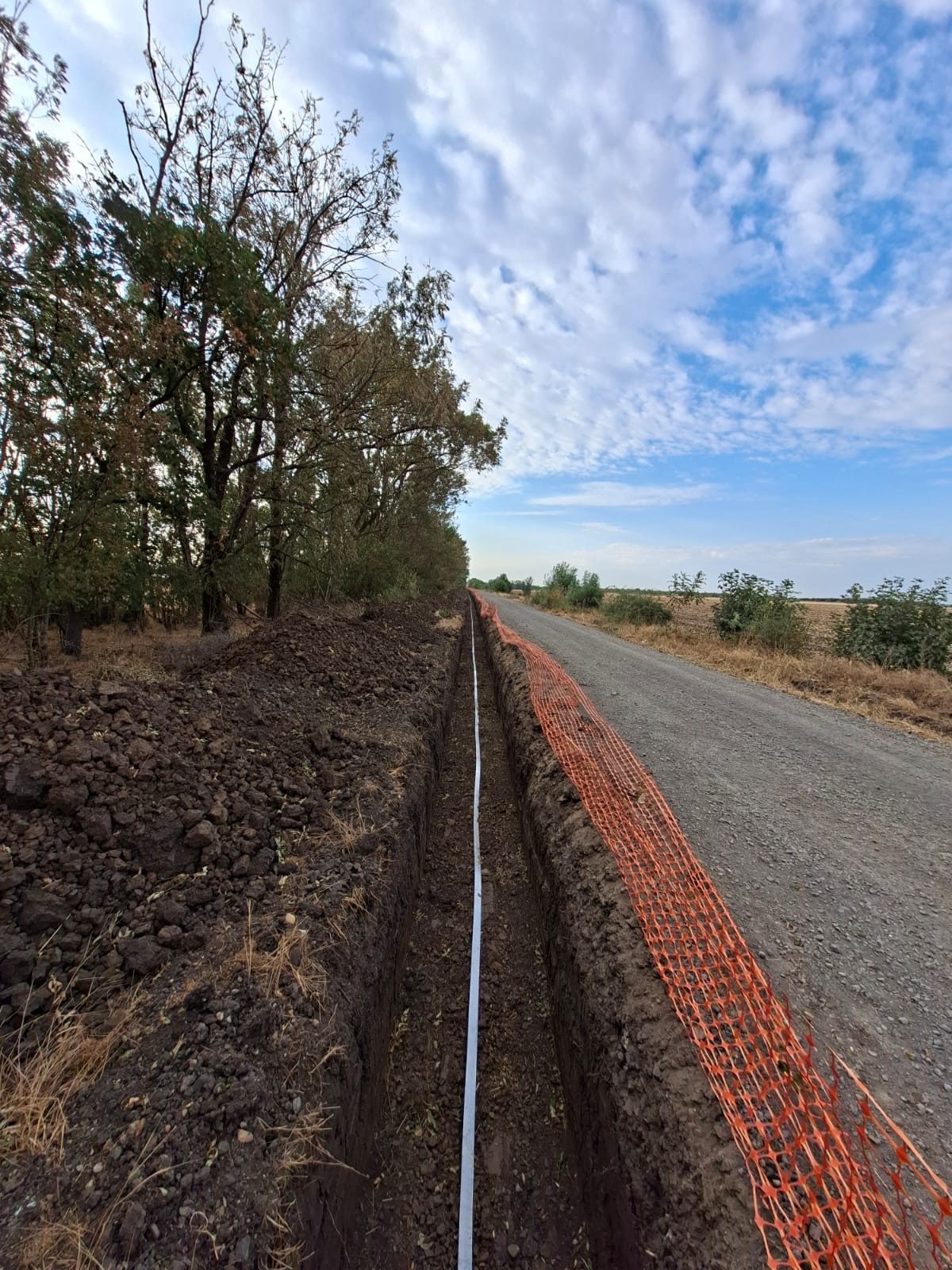 Long cable trench along a site road with earthing strip